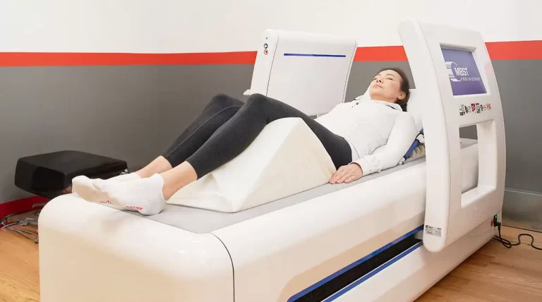 A woman lies down on an MBST machine to receive neuropathy treatment